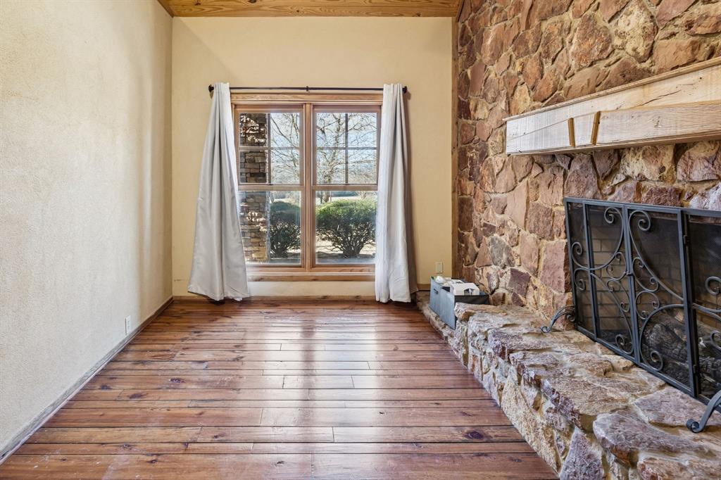 1922 A Bethel-Cannon Road Whitewright, TX 75491 - Photo 17 of 40 Wood-finish flooring throughout, featuring a stone fireplace with a wood mantle, and a large window with wood framing