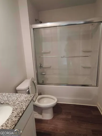 a bathroom with a granite countertop bathtub shower sink and toilet