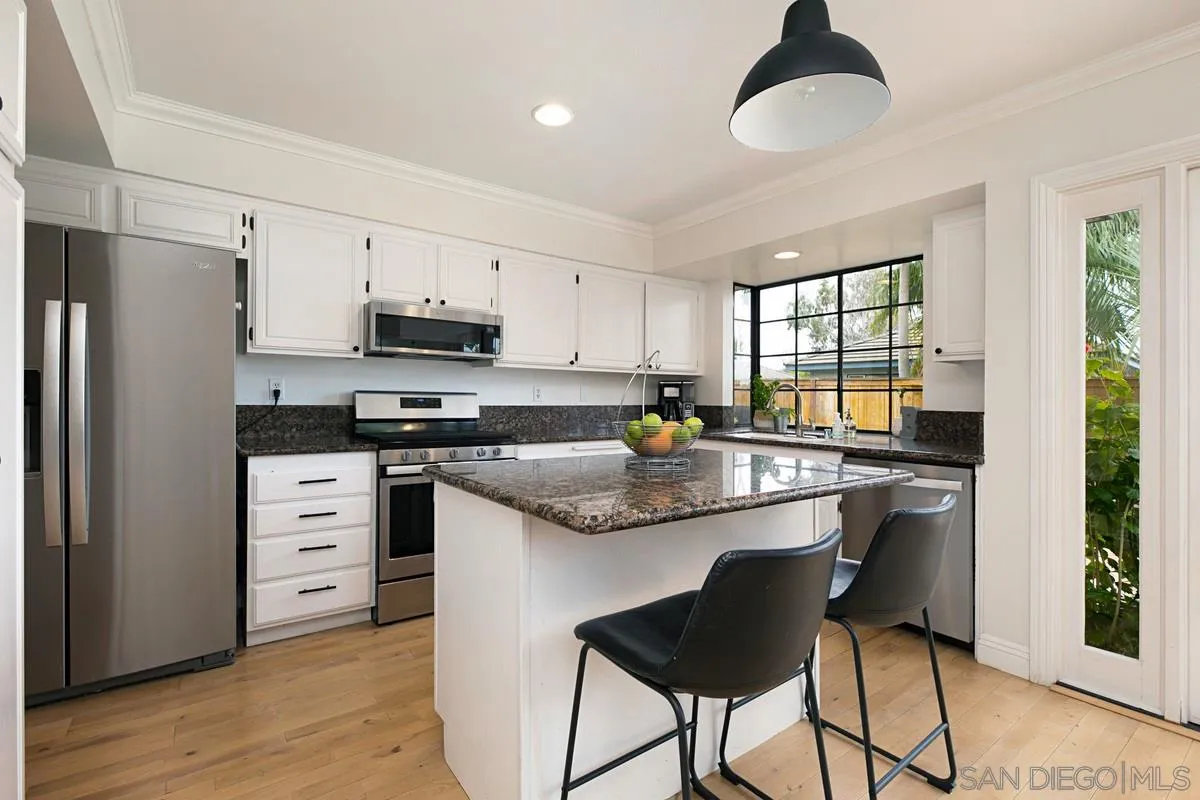 1265 Longfellow Road Vista, CA 92081 - Photo 10 of 28 a kitchen with granite countertop white cabinets refrigerator and dining table