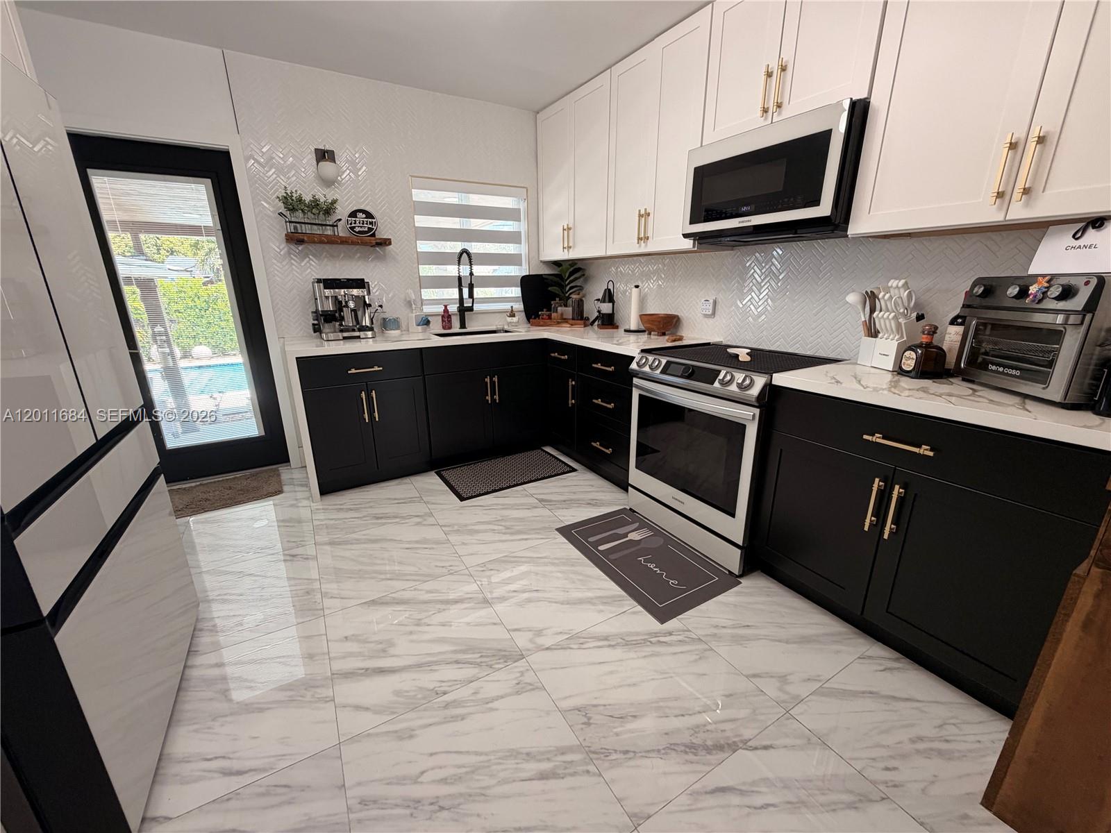 315 West 62nd Street Hialeah, FL 33012 - Photo 5 of 21 a kitchen with stainless steel appliances granite countertop a refrigerator stove a sink dishwasher and white cabinets with wooden floor
