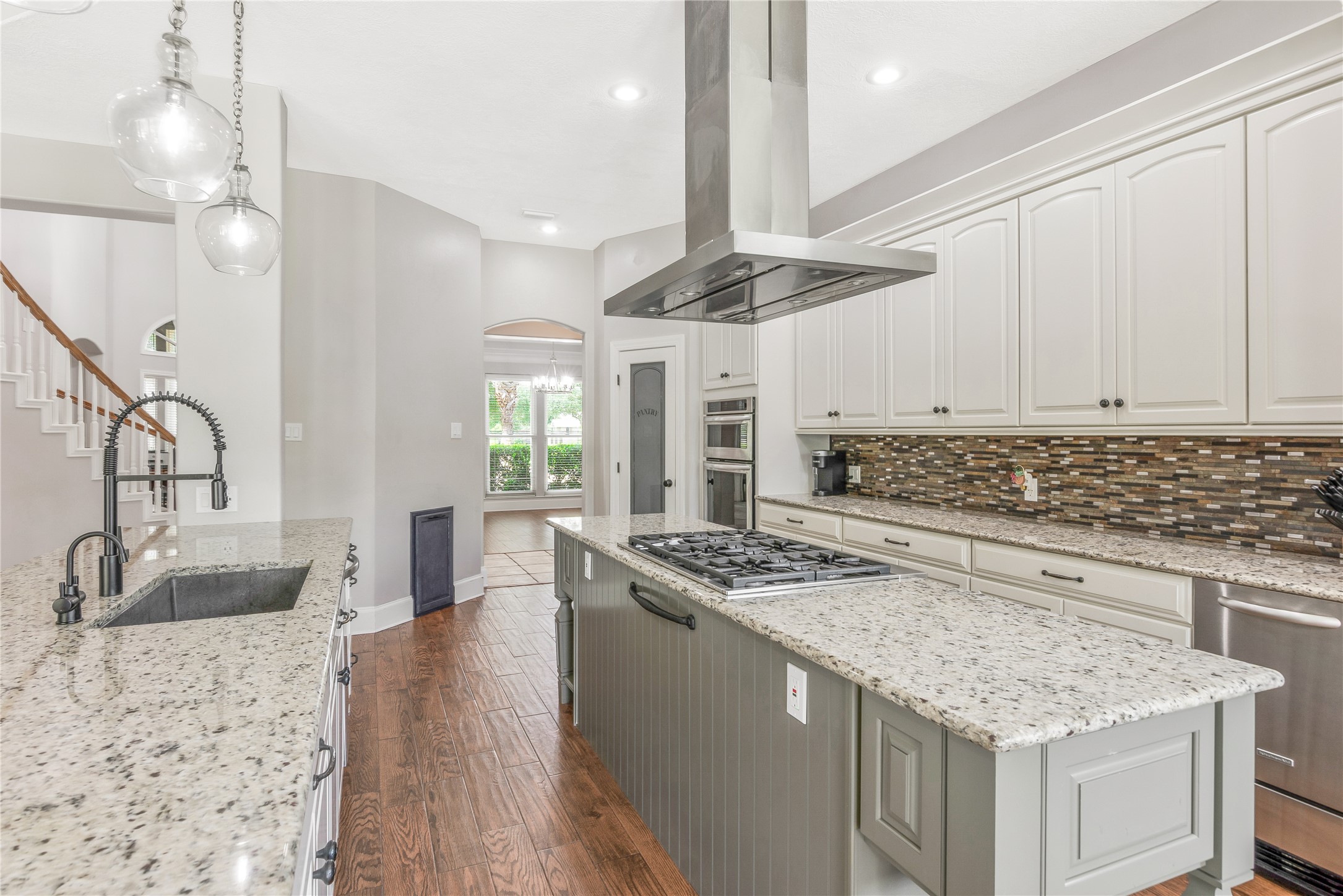 13914 Skinner Road Cypress, TX 77429 - Photo 13 of 50 Long kitchen with white cabinetry, granite countertops, stainless steel appliances, pendant lighting, and hardwood floors.
