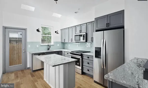 a kitchen with kitchen island granite countertop a sink stove and refrigerator