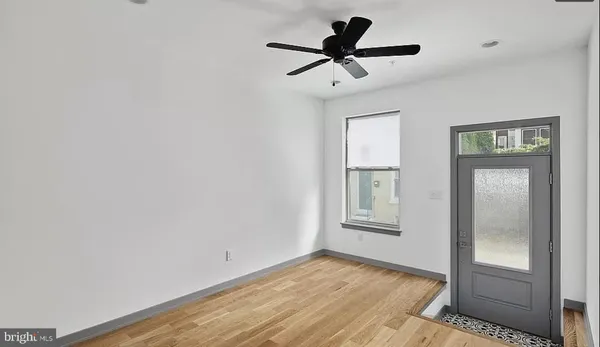 a view of empty room with wooden floor and ceiling fan