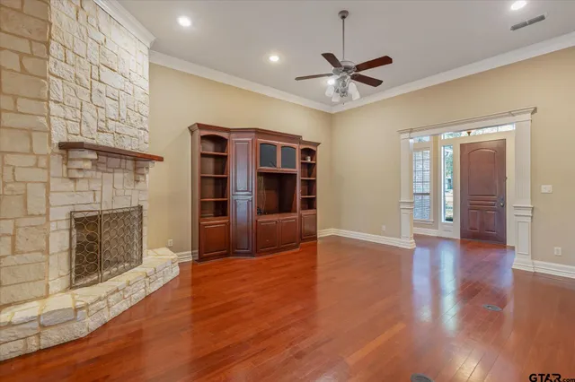 a view of an empty room with wooden floor a fireplace and a window