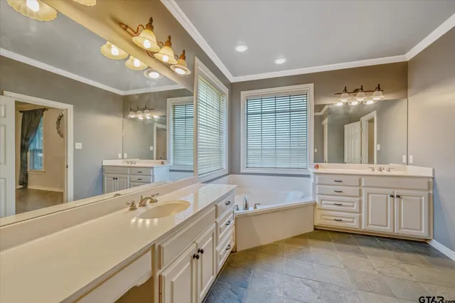 a spacious bathroom with a double vanity sink a large mirror and a bathtub