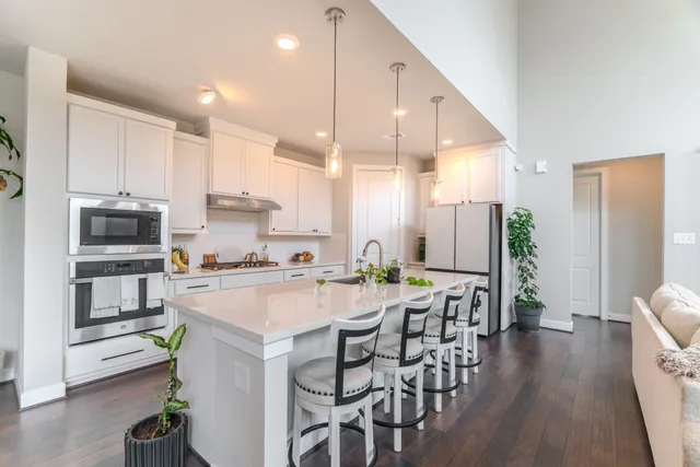 a kitchen with stainless steel appliances a dining table chairs stove refrigerator and wooden floor