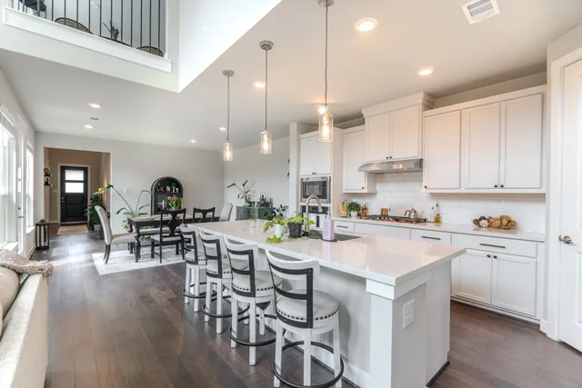 a kitchen with a dining table chairs wooden floor appliances and cabinets