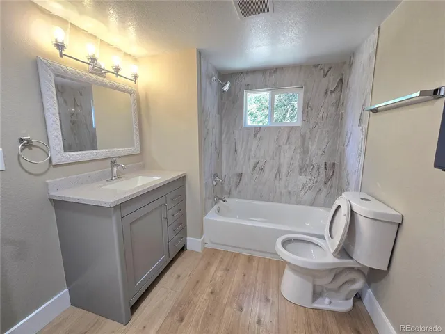 a bathroom with a bathtub sink mirror vanity and toilet