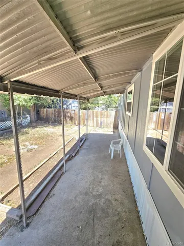 a view of an empty room with wooden floor and a bed