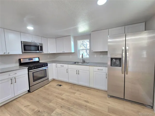 a kitchen with granite countertop white cabinets and stainless steel appliances