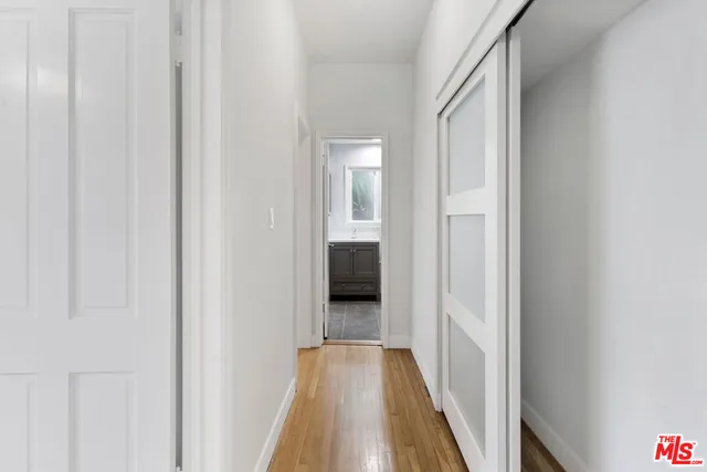 a view of a hallway with wooden floor and a bathroom
