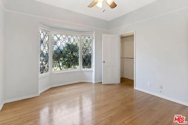 a view of an empty room with a window and wooden floor