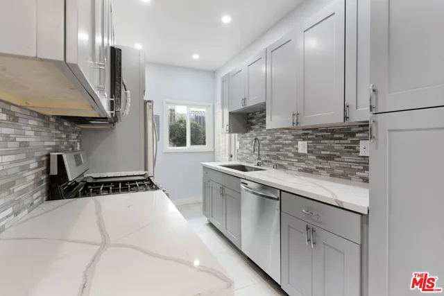 a kitchen with kitchen island granite countertop a sink a stove and cabinets