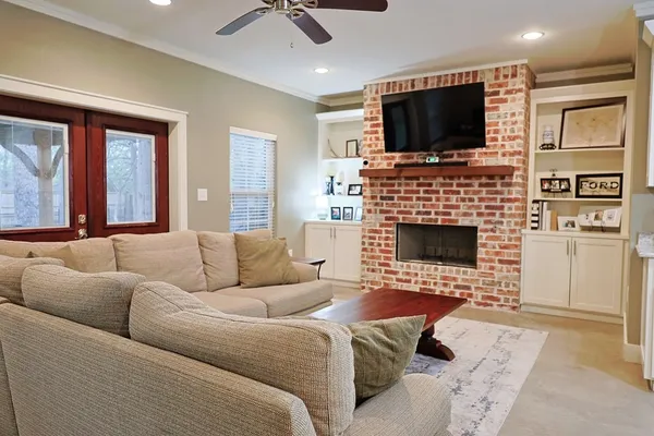 a living room with fireplace a flat screen tv and a ceiling fan