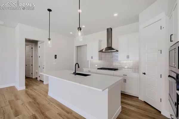a kitchen with stainless steel appliances a stove a sink a refrigerator and a wooden floor