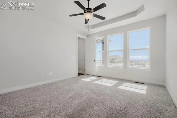 an empty room with windows and fan
