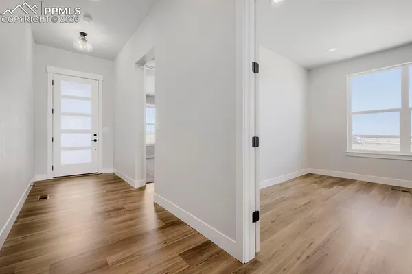 an empty room with wooden floor & cabinet and windows