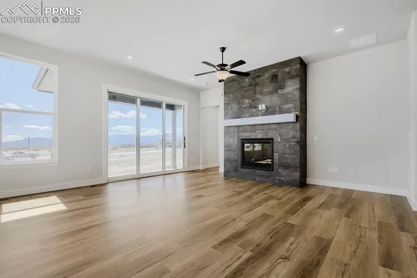 a view of an empty room with wooden floor fireplace and a window