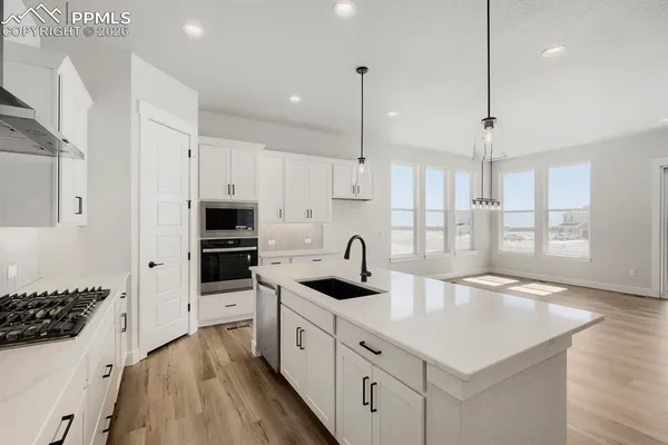 a kitchen with granite countertop a sink a counter space appliances and cabinets