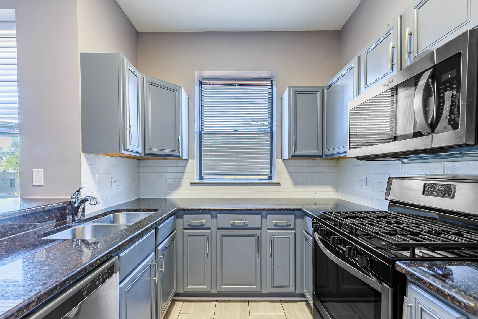 3704 South King Drive, Unit 3C Chicago, IL 60653 - Photo 7 of 26 a kitchen with stainless steel appliances granite countertop white cabinets and window