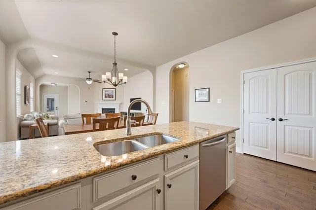 a kitchen with granite countertop a sink a counter top space and living room view