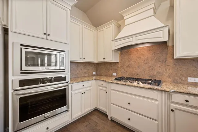a kitchen with white cabinets and appliances