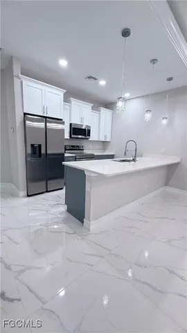 a large kitchen with kitchen island a large counter top stainless steel appliances and cabinets