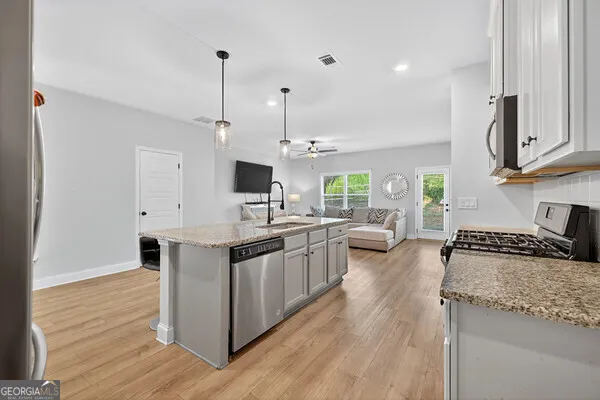a kitchen with stainless steel appliances granite countertop a sink stove and wooden floor
