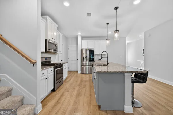 a large kitchen with stainless steel appliances kitchen island granite countertop a stove a sink a refrigerator and a wooden cabinets