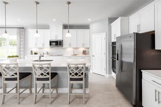 a kitchen with stainless steel appliances a refrigerator a stove a sink a dining table and chairs