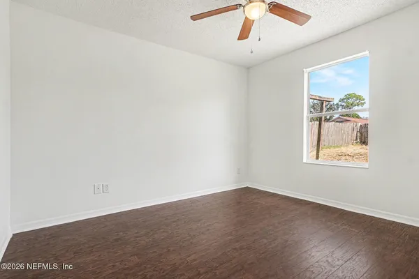 an empty room with a window and a ceiling fan