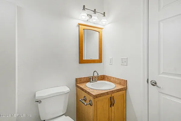 a bathroom with a granite countertop sink toilet and mirror