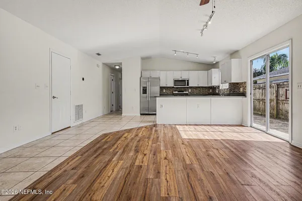 a large kitchen with cabinets wooden floor and stainless steel appliances