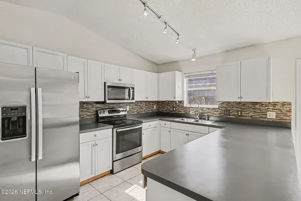 a kitchen with a sink stainless steel appliances and white cabinets