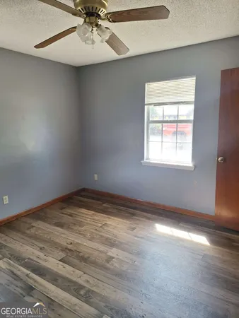 an empty room with a chandelier fan and windows