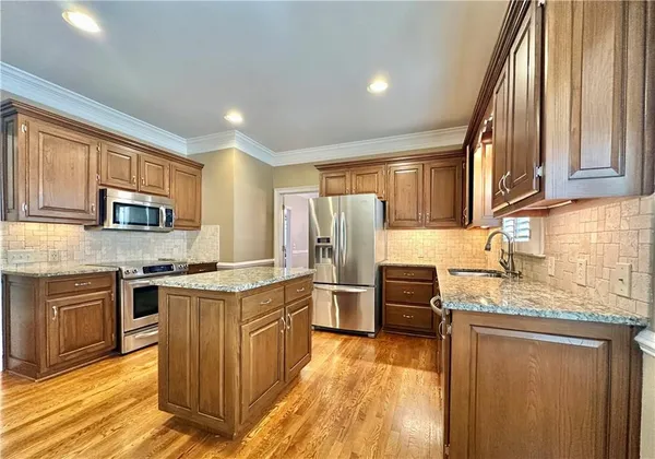 a kitchen with stainless steel appliances granite countertop a stove top oven a refrigerator a sink and dishwasher