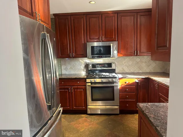 a kitchen with granite countertop wooden cabinets and stainless steel appliances