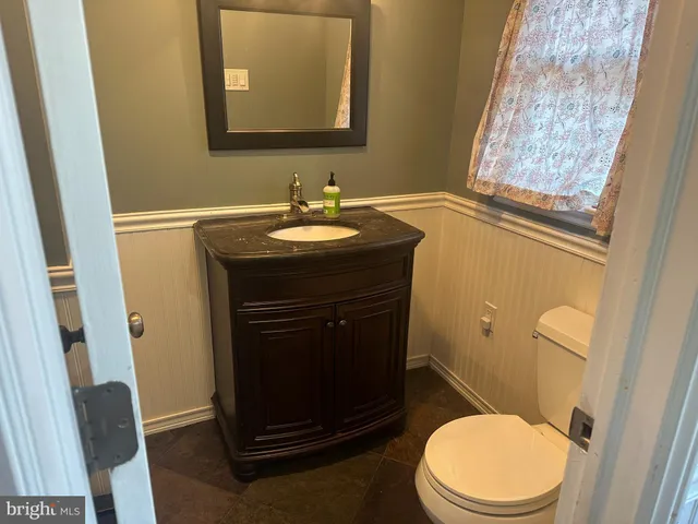 a bathroom with a granite countertop toilet sink and mirror