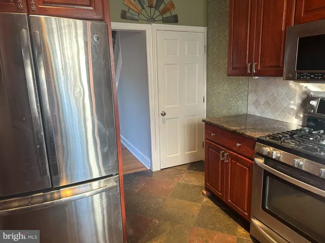 a kitchen with granite countertop a refrigerator and a stove top oven