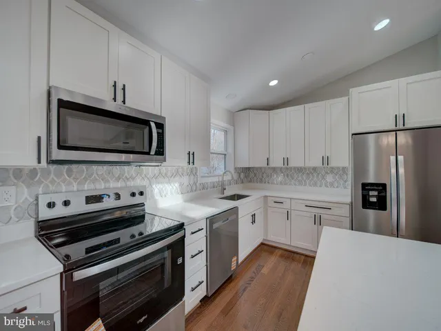 a kitchen with sink a refrigerator and white cabinets