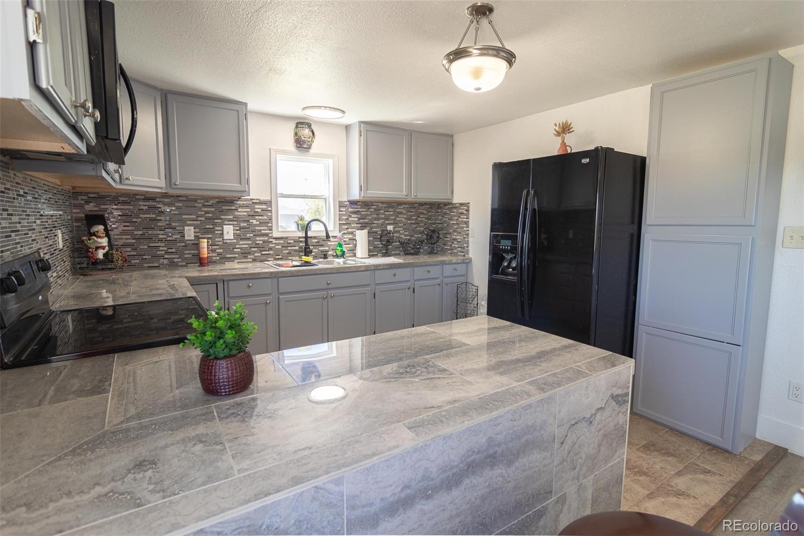 3425 Wiesner Road Calhan, CO 80808 - Photo 6 of 22 a kitchen with stainless steel appliances kitchen island granite countertop a refrigerator a stove a sink dishwasher and a refrigerator with wooden floor