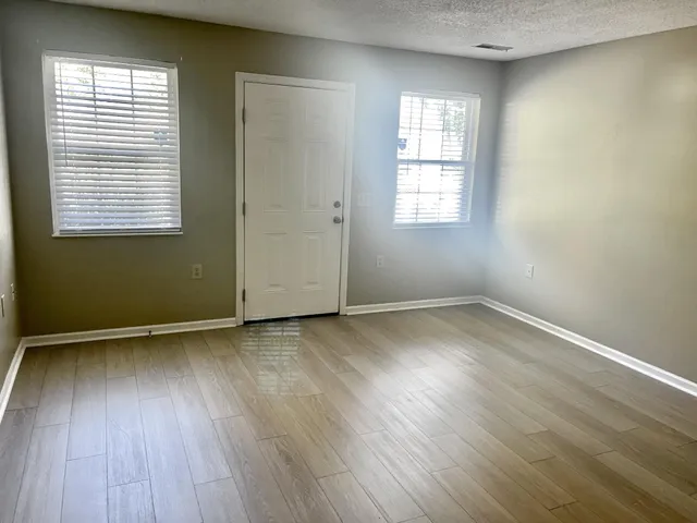 an empty room with wooden floor and windows