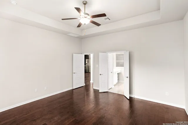 an empty room with wooden floor and ceiling fan