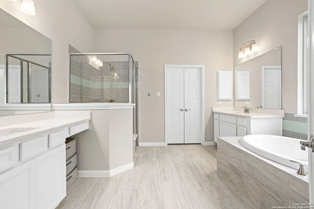 a spacious bathroom with a double vanity sink a mirror and a shower