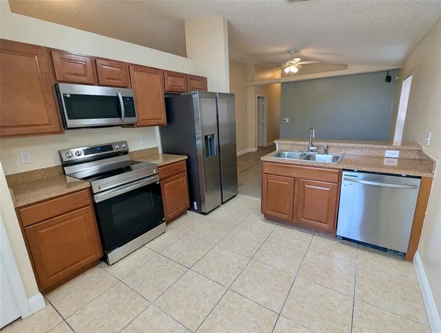 a kitchen with stainless steel appliances granite countertop a stove top oven a sink and a refrigerator