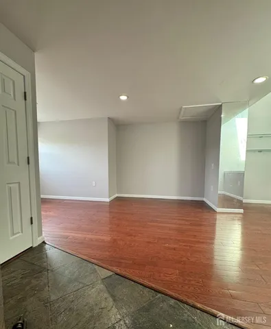 a view of an empty room with wooden floor and closet