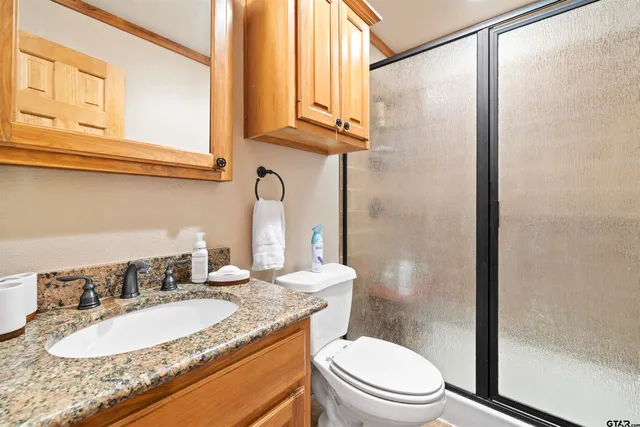 a bathroom with a granite countertop sink a toilet and shower