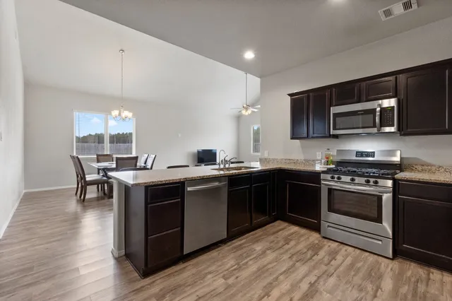 a kitchen with kitchen island granite countertop a sink refrigerator and microwave