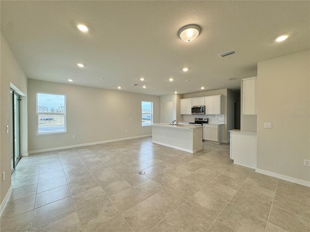 3703 Haddon Avenue Davenport, FL 33837 - Photo 22 of 23 a view of kitchen with kitchen island stainless steel appliances refrigerator stove microwave and white cabinets