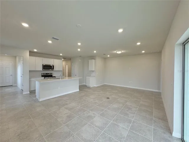a view of kitchen with kitchen island stainless steel appliances refrigerator oven a sink and white cabinets
